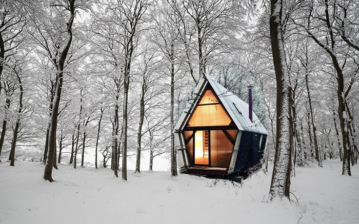 Modern A-frame cabin in a snowy forest