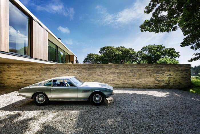 Modern house with a vintage car parked on gravel