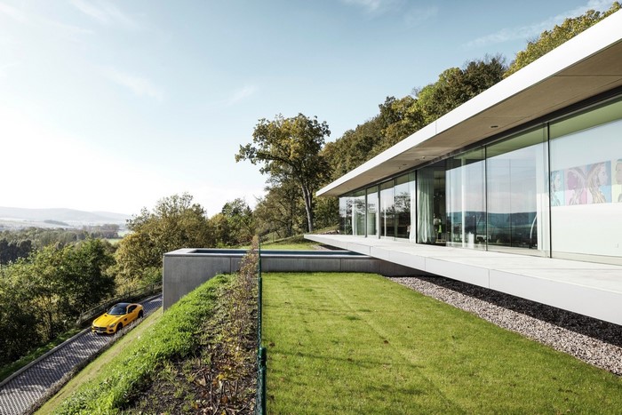 Yellow Mercedes-AMG GT drives up a modern house driveway