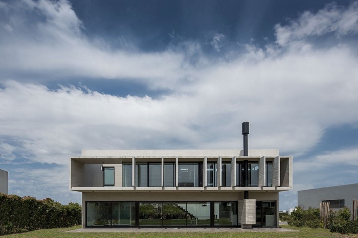 Modern concrete house with large windows and chimney