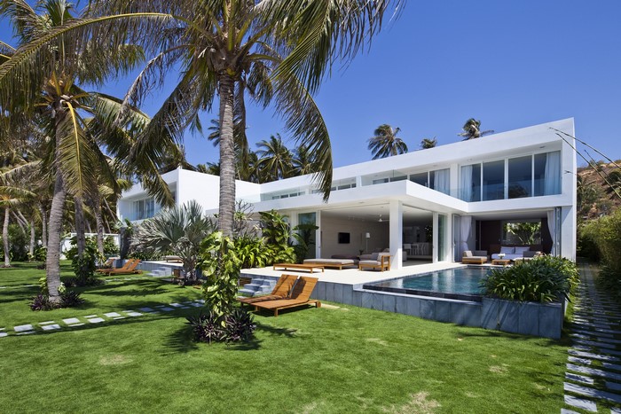 Modern white mansion with palm trees and swimming pool