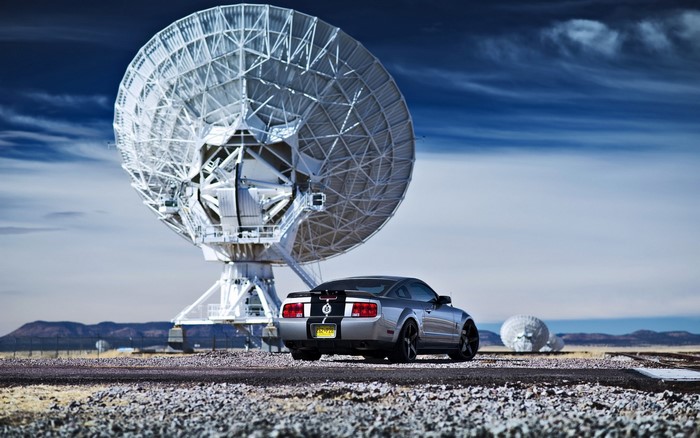 Ford Mustang parked near large satellite dishes