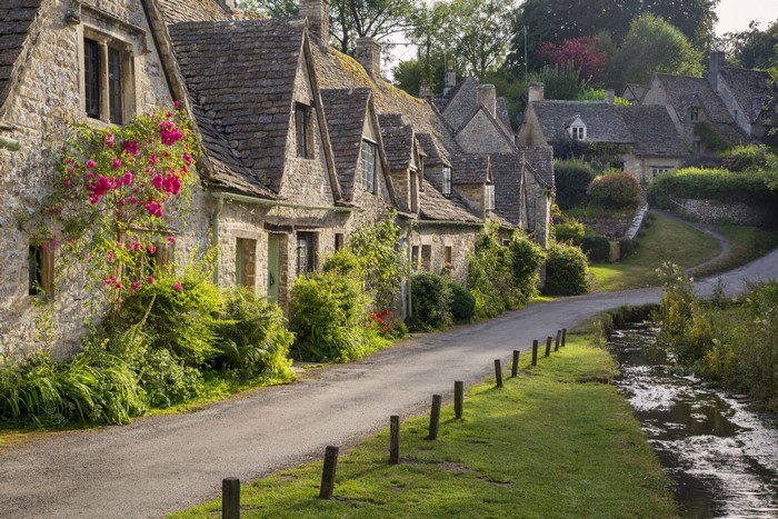 Stone cottages with flowers and a stream in the Cotswolds, England