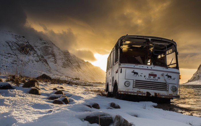 Abandoned Ford Campingbil bus in snowy mountains at sunset