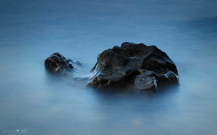 Dark rocks in blue water with long exposure