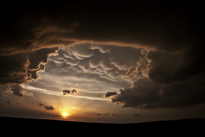 Mammatus clouds at sunset over a dark horizon
