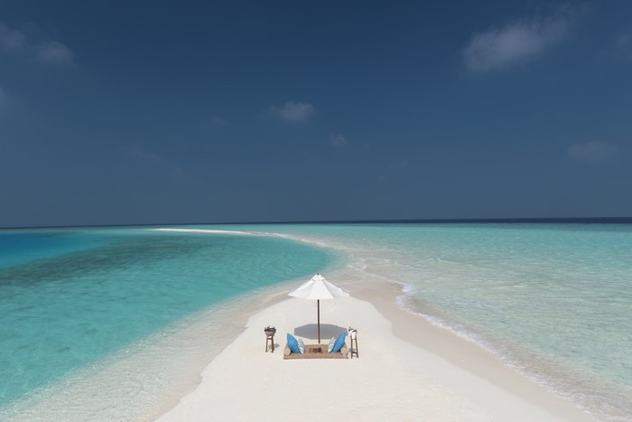 Tropical island sandbar with beach chairs and umbrella