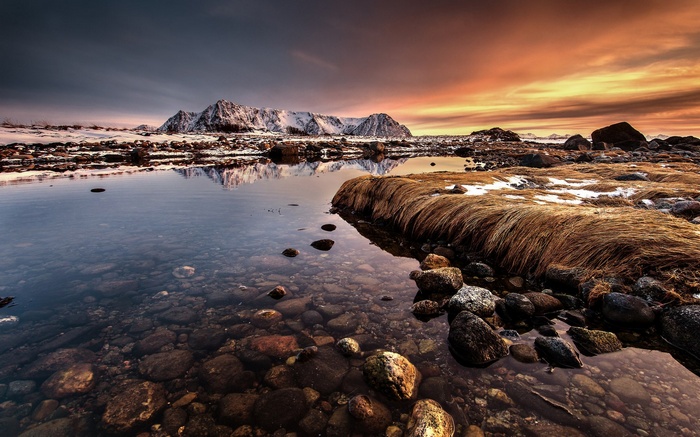 Snowy mountains reflected in water at sunset