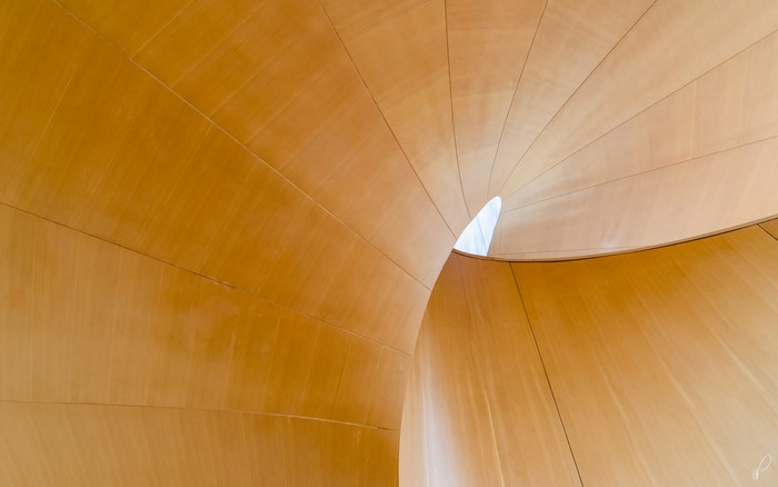 Curved wooden interior with a small opening