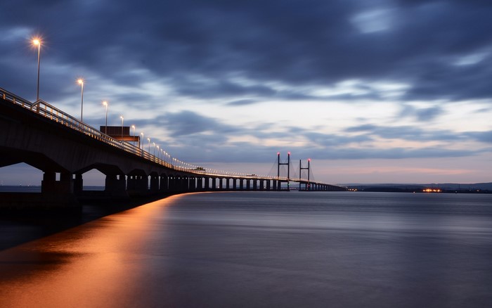 Bridge over water at dusk with clouds