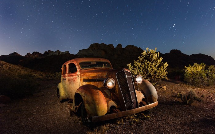 Rusted vintage car under starry desert sky