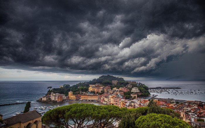 Coastal town under stormy clouds with boats in the sea