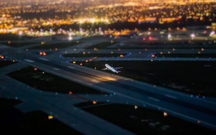 Airplane taking off from runway at night with city lights