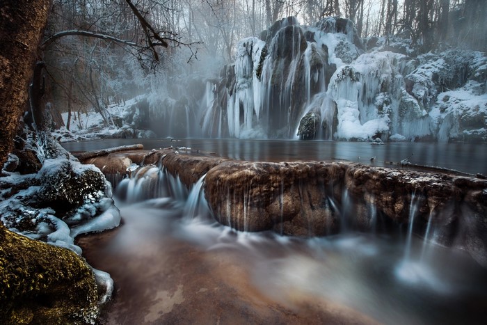 Frozen waterfall in a winter forest with ice formations