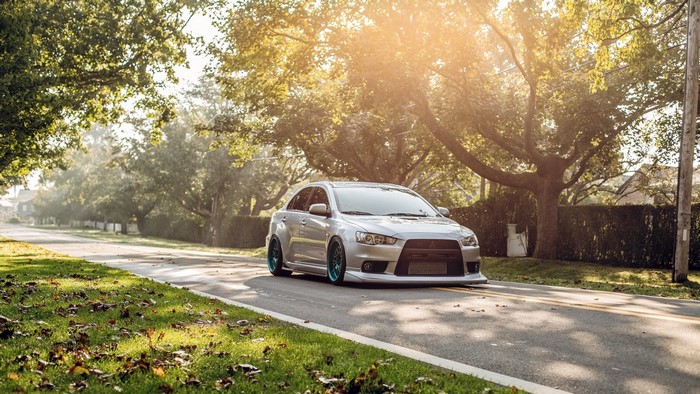 Silver Mitsubishi Lancer EVO with colored wheels on a road