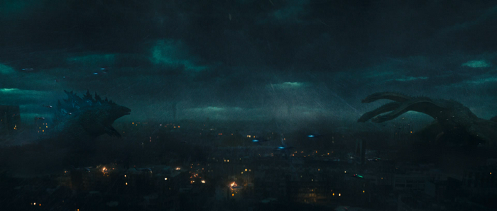 Godzilla and King Ghidorah battle over a city at night
