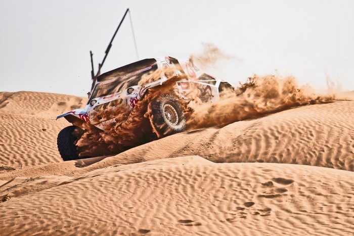 Off-road race car kicking up sand in the desert