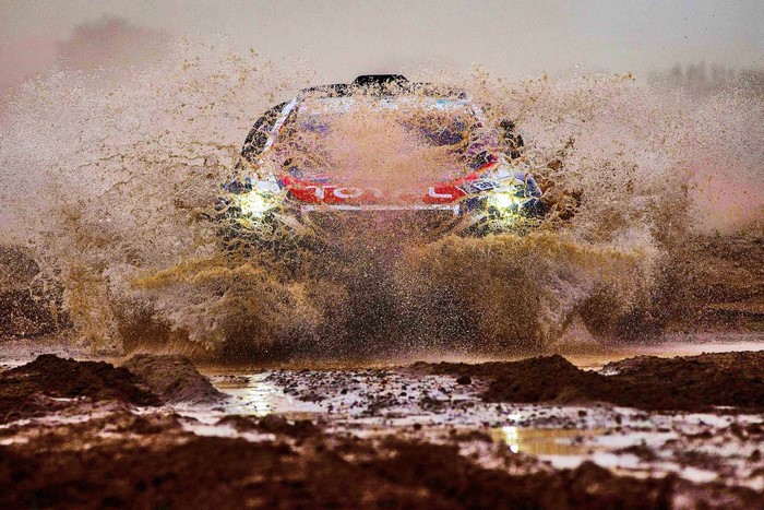 Rally car driving through mud and water