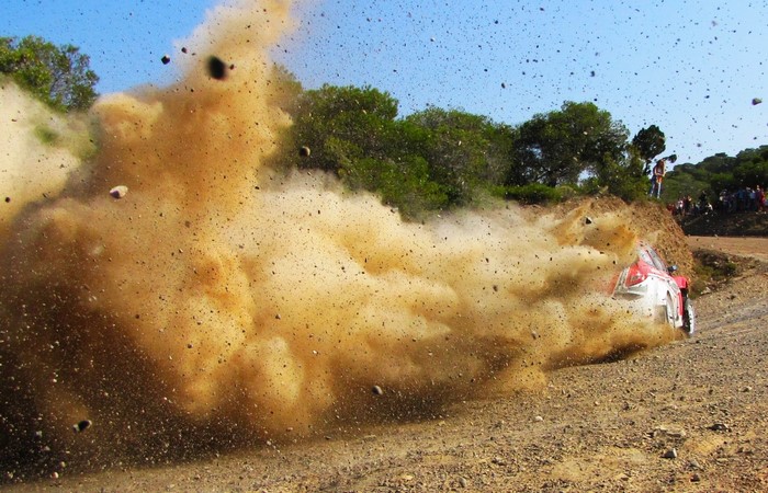 Rally car kicking up dust on a dirt track