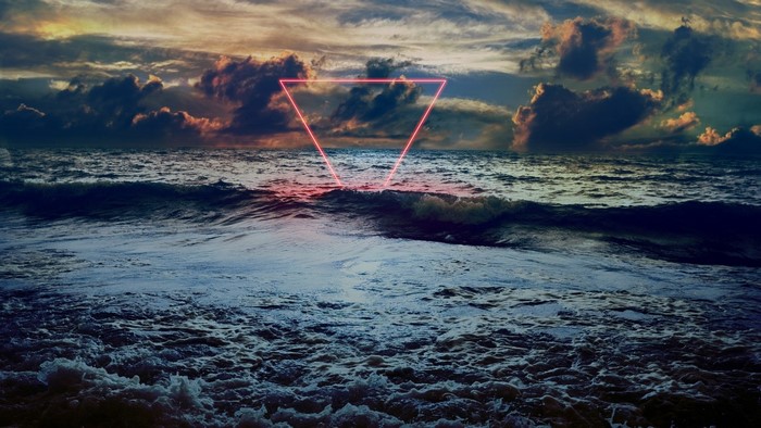 Neon triangle over stormy sea at sunset