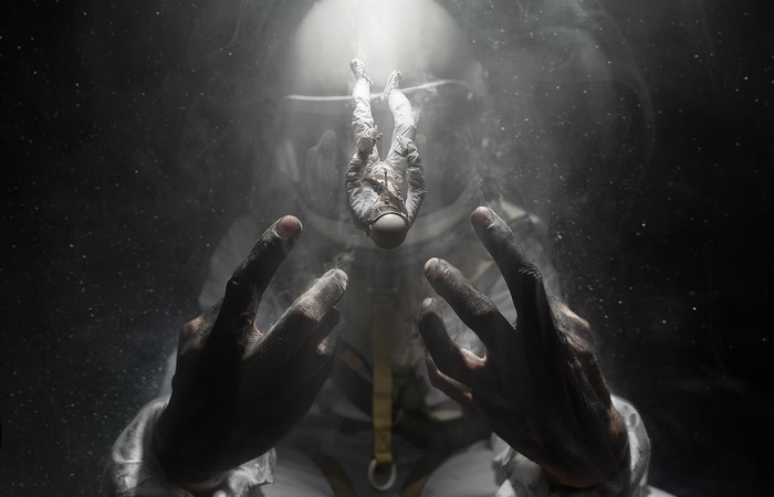 Astronaut floating in space with hands reaching out