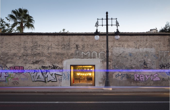 Graffiti-covered wall with an illuminated entrance and street lamp