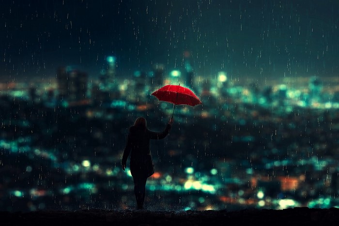 Woman with red umbrella in the rain at night