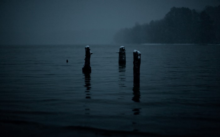 Gloomy winter lake with snow falling