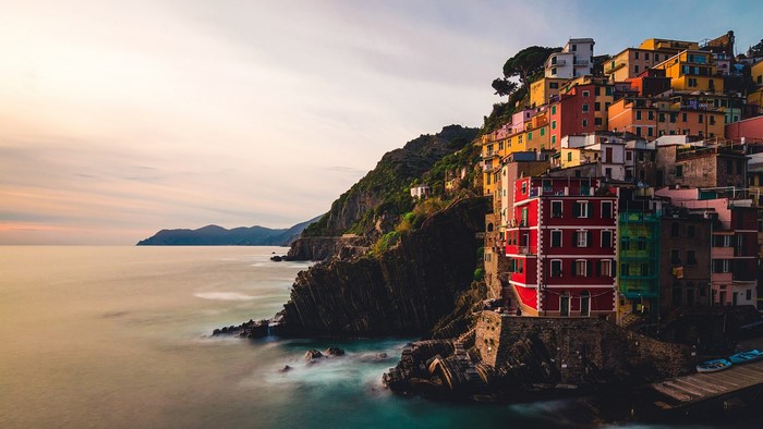 Colorful houses on a cliff overlooking the sea in Riomaggiore, Italy at sunset