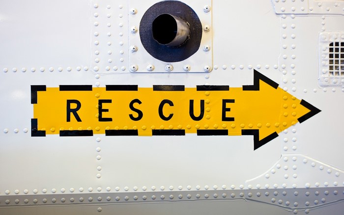 Yellow rescue arrow sign on white surface