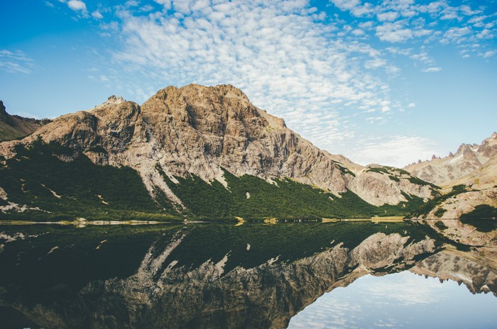 Mountain range reflected in a calm lake under a cloudy sky