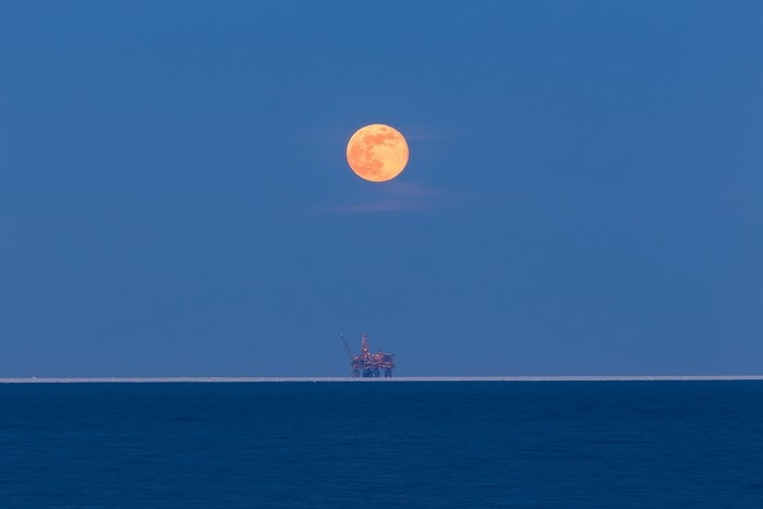 Orange moon over oil platform on the sea