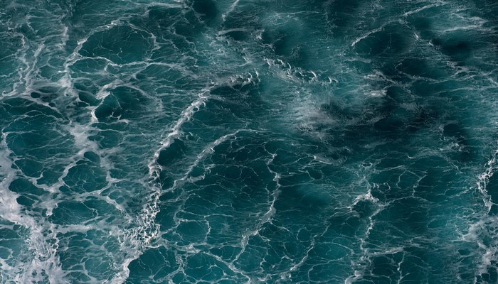Close-up of turbulent blue ocean water with white foam