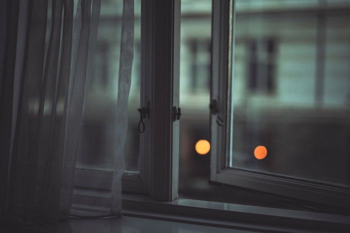 Window with sheer curtains and bokeh lights at night