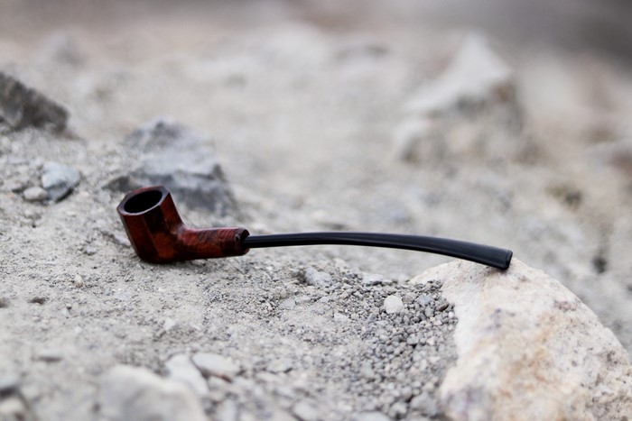Wooden smoking pipe on rocks