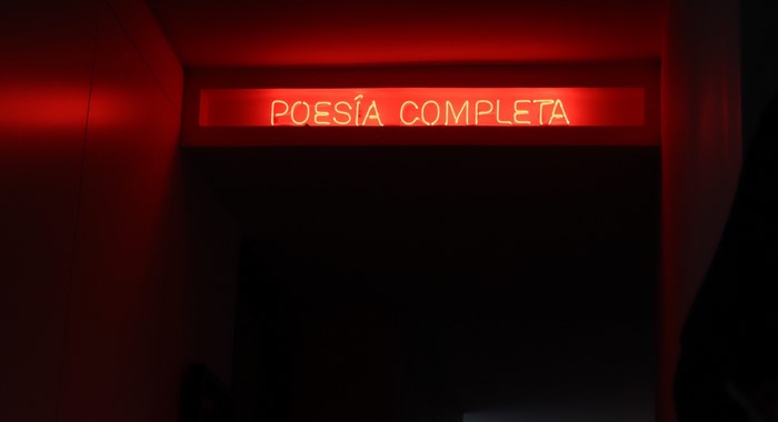Red neon sign that says POESÍA COMPLETA