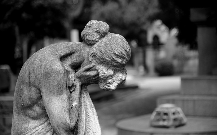 Monochrome statue of a grieving woman in a cemetery