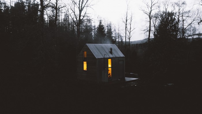 Cabin in a dark forest with smoke from chimney