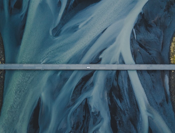 Aerial view of a bridge over a river with a vehicle