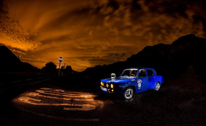 Blue rally car at night with stop sign