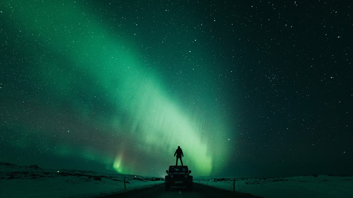Kristopher Roller standing on car under aurorae