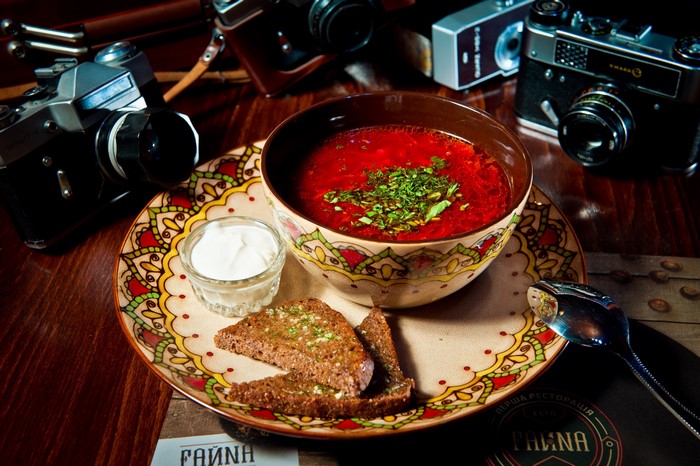 Borscht soup with bread and sour cream on a decorative plate