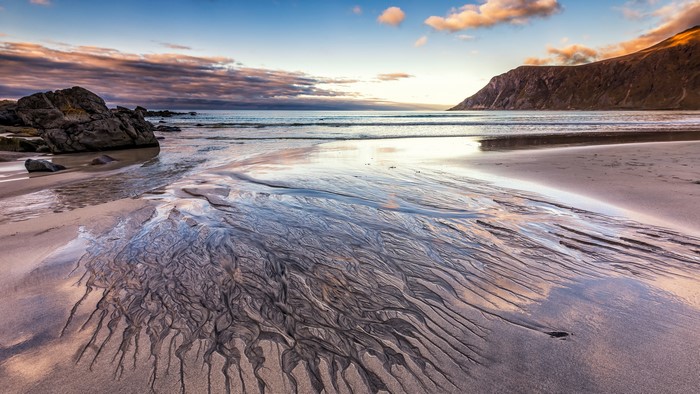 Beach with sand patterns and mountain at sunset