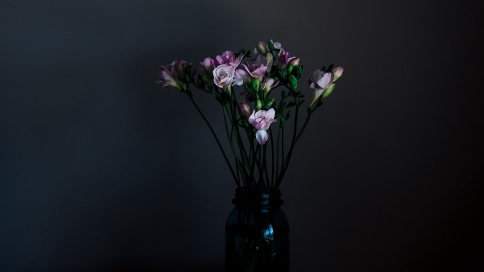 Bouquet of pink freesia flowers in a dark vase