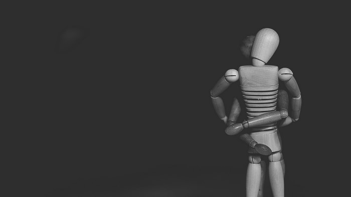 Two wooden mannequins in a hug