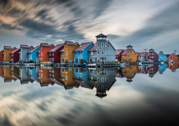 Colorful houses reflected in water with streaky clouds