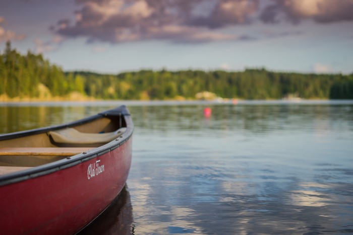 Red canoe on a calm lake with forest background