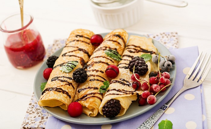 Chocolate drizzled crepes with berries and jam