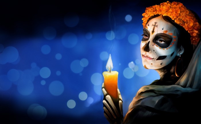 Woman with Dia de los Muertos makeup holding a candle