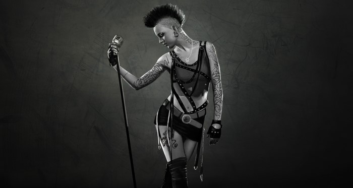 Woman with mohawk and tattoos holding a microphone